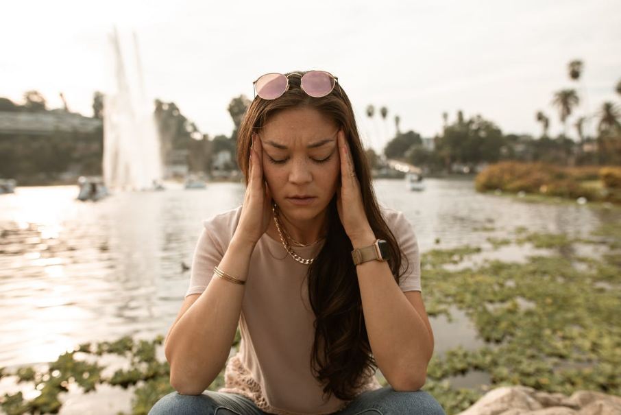 woman-in-gray-t-shirt-and-blue-denim-jeans-wearing-pink-sunglasses-sitting-on-rock-during