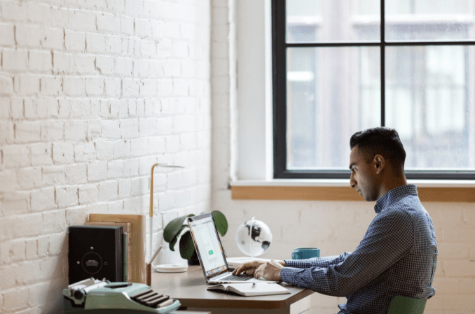 man-sitting-on-green-chair-while-using-laptop