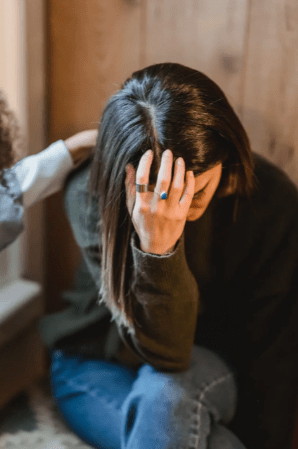 tired-woman-touching-forehead-while-friend-soothing