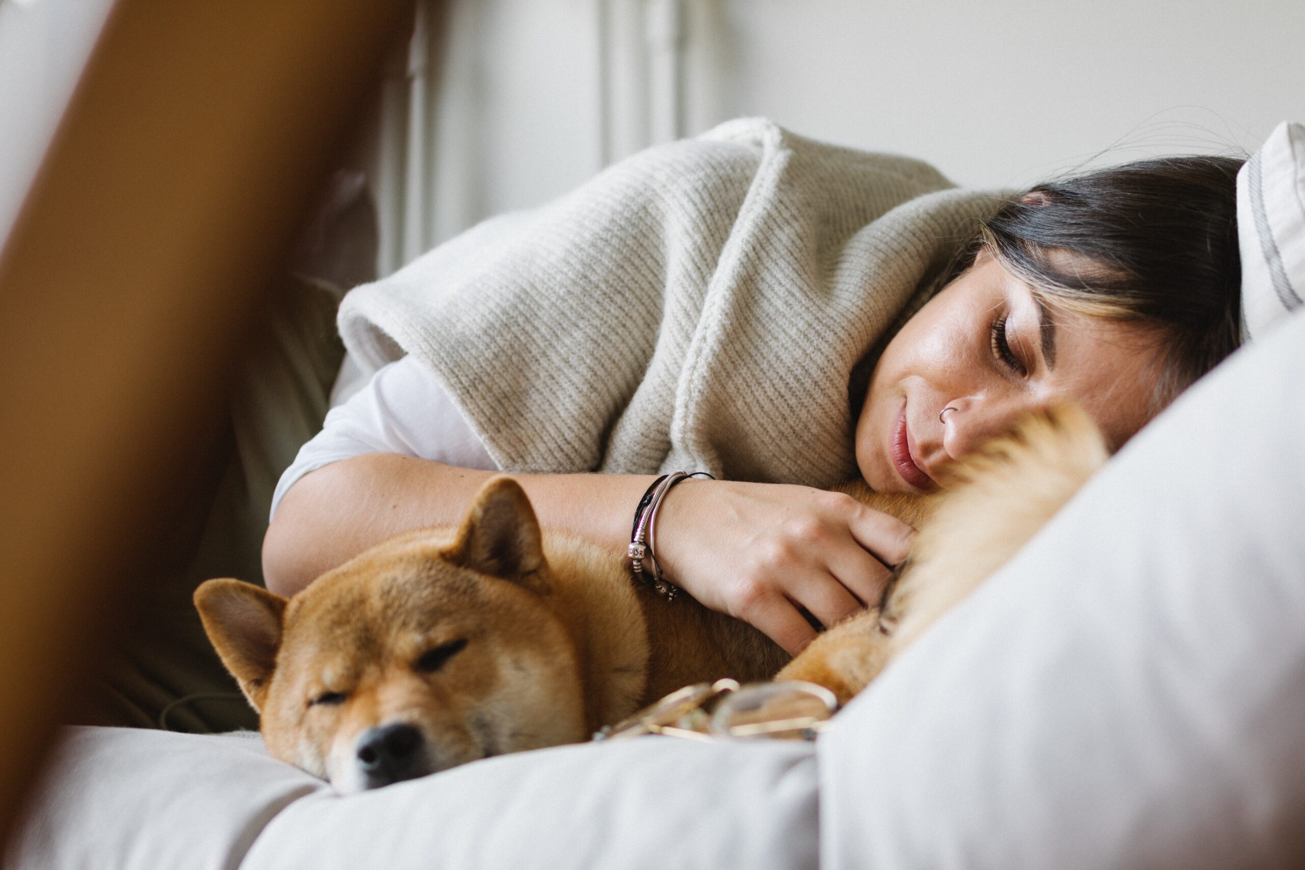 A woman lying on the couch with her dog