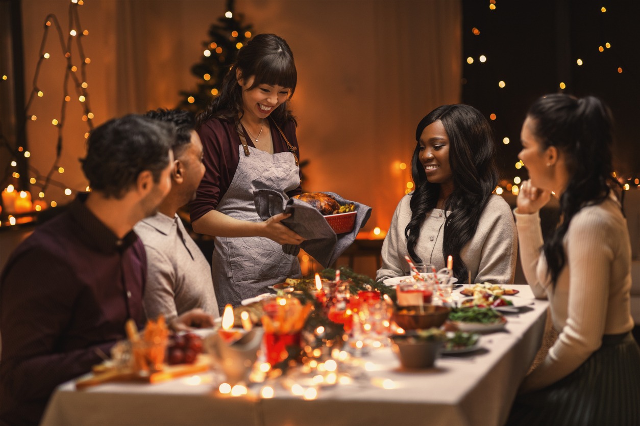 Multiethnic group of happy friends having Christmas dinner at home