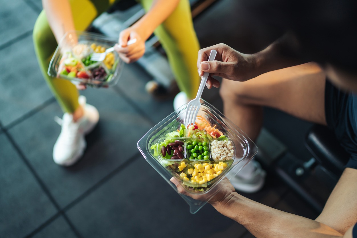 a man and woman eating salad after exercise