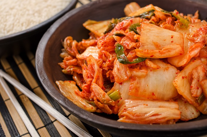 Plate full of kimchi and chopsticks on side
