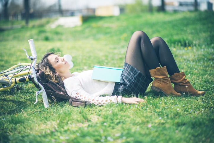 Woman with bicycle reading book in park