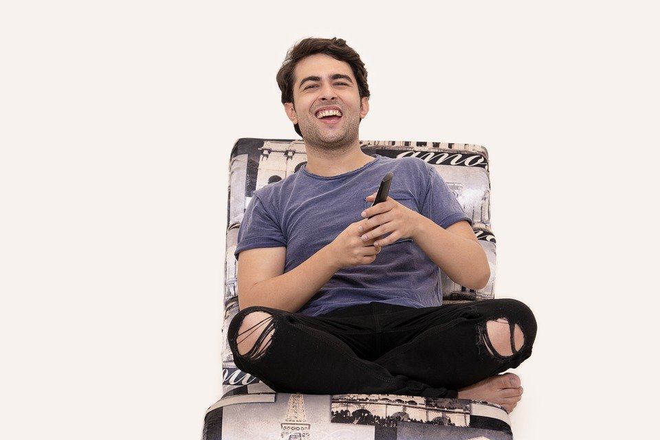 a man laughing while holding the television remote control