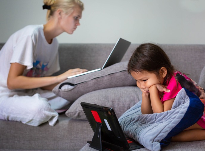 A family on their computers watching tv and working at home. Technology.