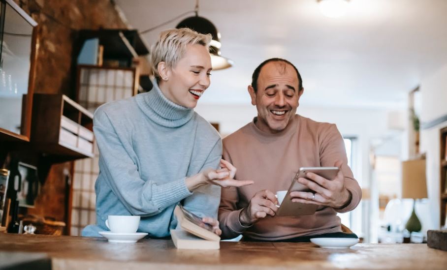joyful-multiracial-spouses-laughing-while-watching-funny-movie-on-tablet