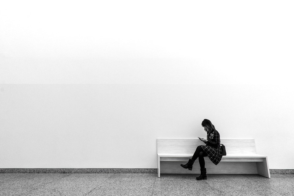 a woman sitting on a bench in front of a large blank wall