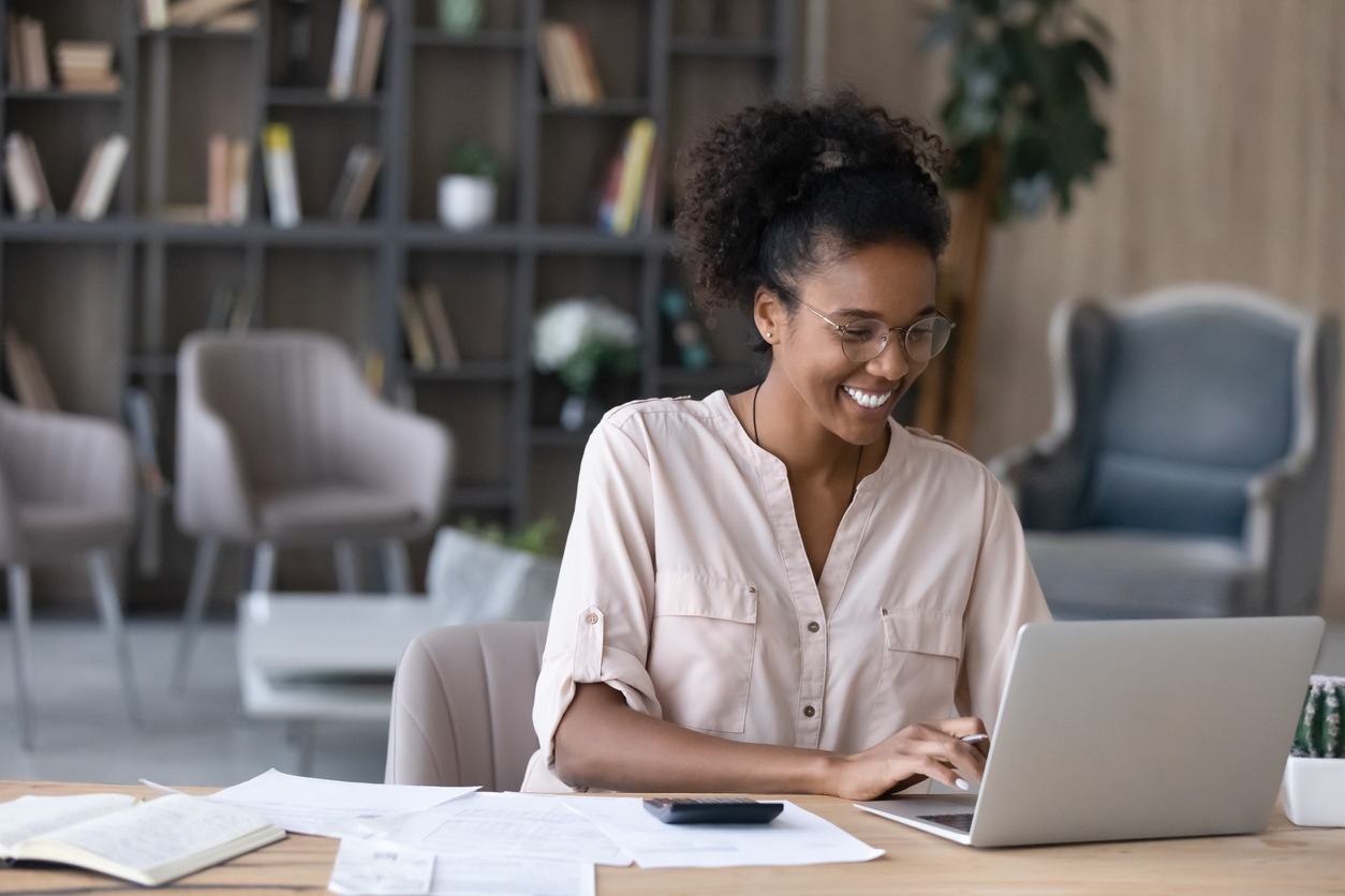 Smiling African American woman manage finances on laptop