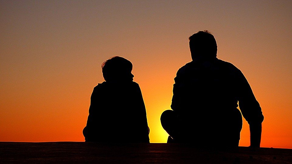 silhouette of father and son while the sun sets