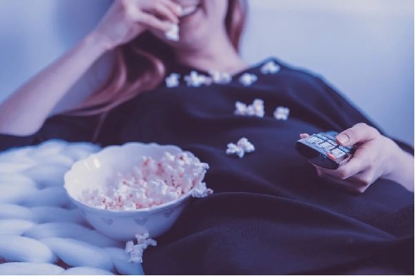 woman watching a movie while eating popcorn