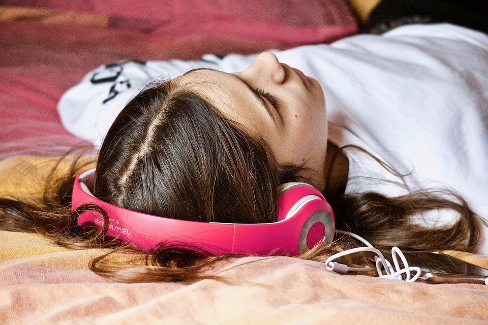 woman listening to music while lying on the bed