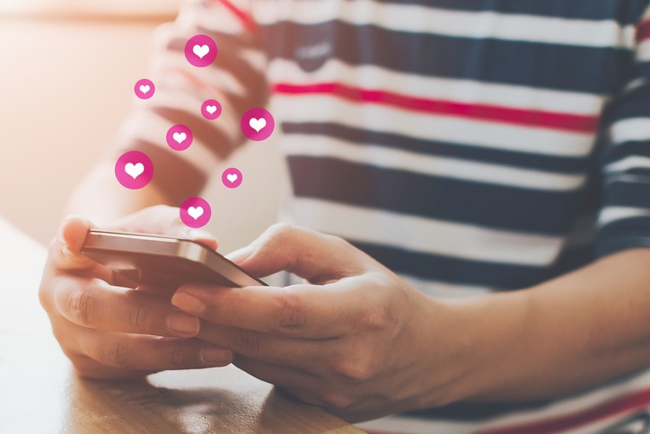 Social network sharing and commenting in the online community, Man hand holding smartphone and using application social media with icon heart