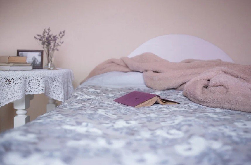 a bed with blanket and a book
