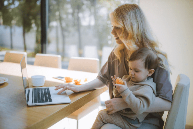 woman-carrying-her-baby-and-working-on-a-laptop