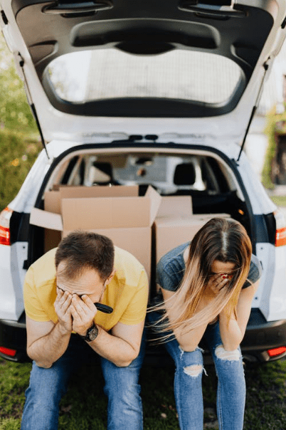 Tired couple sitting on car luggage boot