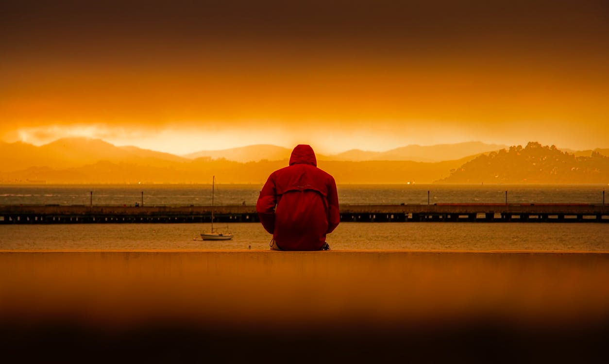 A person in a red hoodie sitting alone