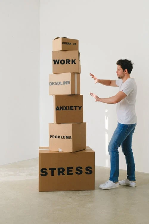 man near carton boxes with many different words about stress)